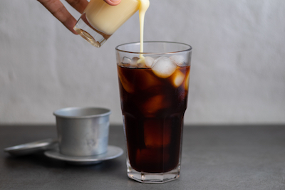 pouring milk in homemade iced coffee