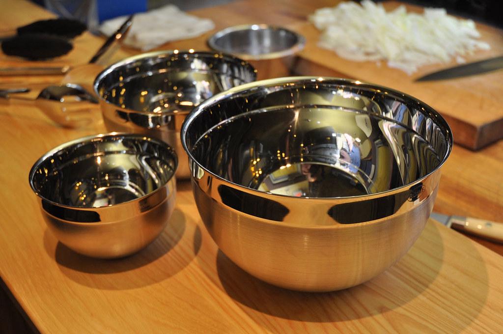 A set of glass and stainless steel mixing bowls in various sizes, some with non-slip bases