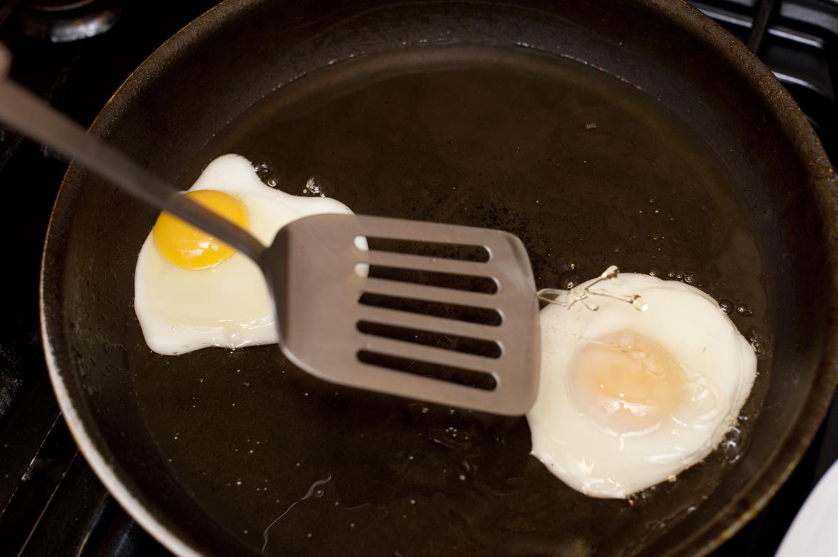 A non-stick skillet with a heavy-gauge aluminum base, cooking a perfectly fried egg